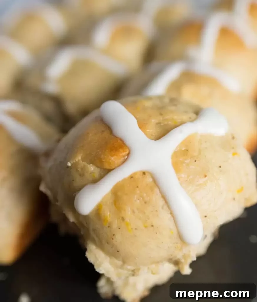 Cranberry Orange Hot Cross Buns Recipe 3 photograph of a hot cross bun with more cranberry orange hot cross buns in the background