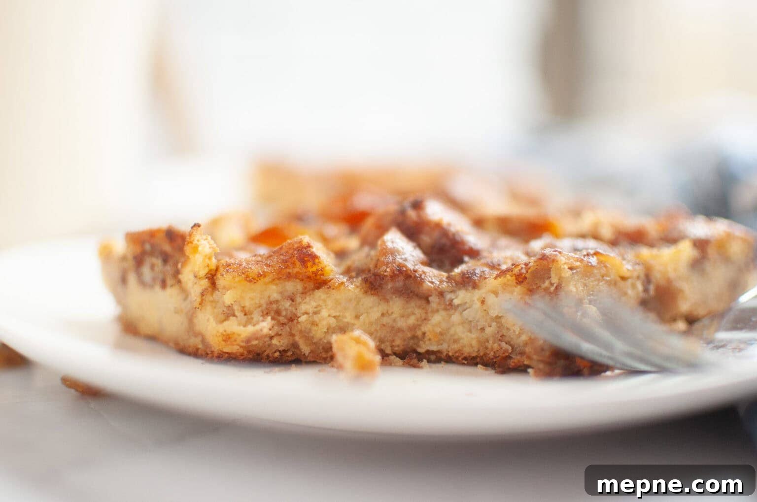 35 Classic Casserole Recipes That Have Everyone Coming Back 13 A close-up of a partially eaten piece of Cinnamon Roll Casserole on a white plate, with a fork resting beside it.