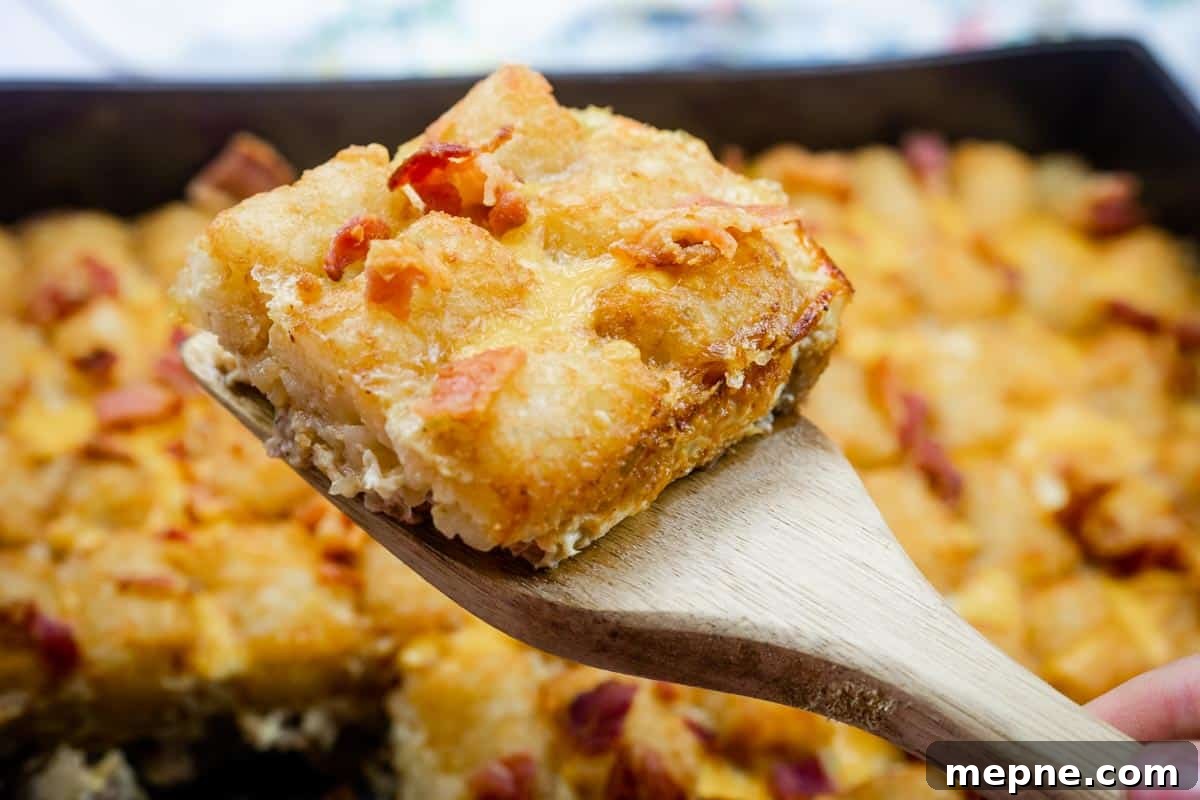 35 Classic Casserole Recipes That Have Everyone Coming Back 14 A wooden spatula holds a square piece of Crispy Tater Tot Breakfast Bake with bits of bacon, with the rest of the casserole visible in the background.