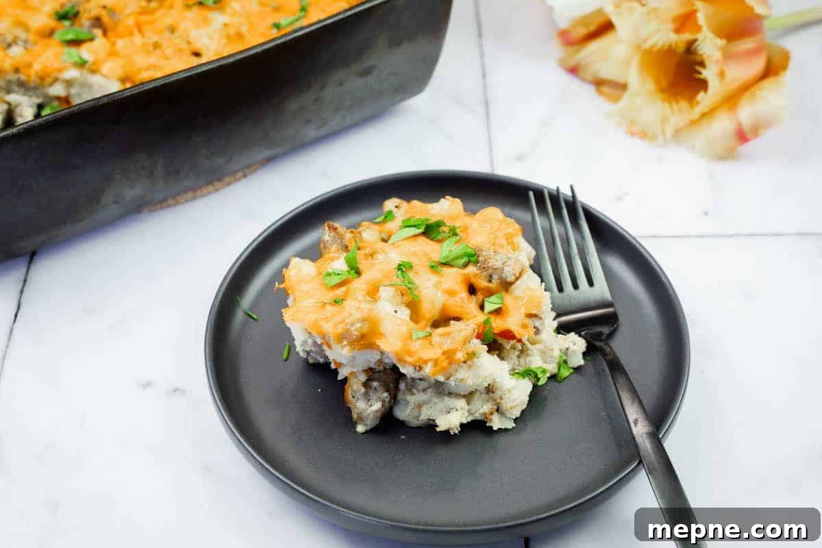 35 Classic Casserole Recipes That Have Everyone Coming Back 19 A serving of Sausage-Hash Brown Breakfast Casserole on a black plate with a fork, next to a baking dish and pasta shells on a marble surface.