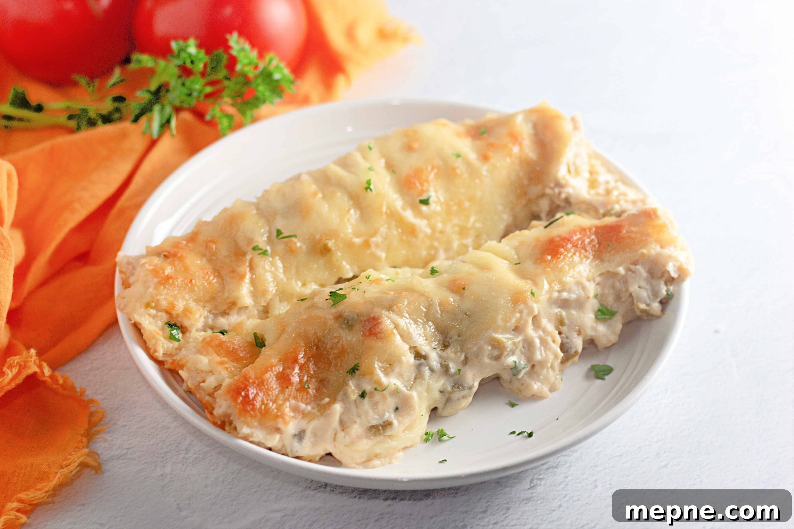 35 Classic Casserole Recipes That Have Everyone Coming Back 20 Two White Chicken Enchiladas filled with creamy sauce and topped with melted cheese, served on a white plate with a garnish of chopped parsley.