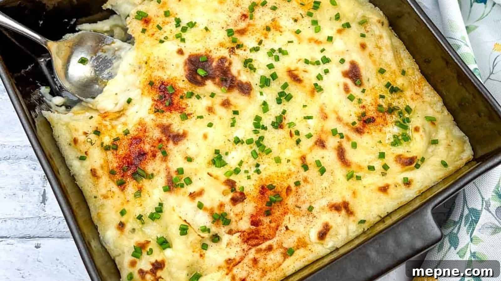 35 Classic Casserole Recipes That Have Everyone Coming Back 25 A close-up of Grandma's Mashed Potato Casserole with a serving spoon in the dish.