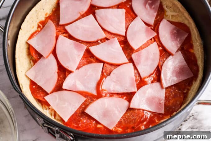 ham slices on pizza sauce. 