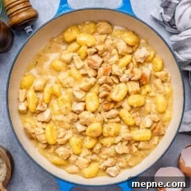 gnocchi and chicken in a creamy sauce in a blue pan.