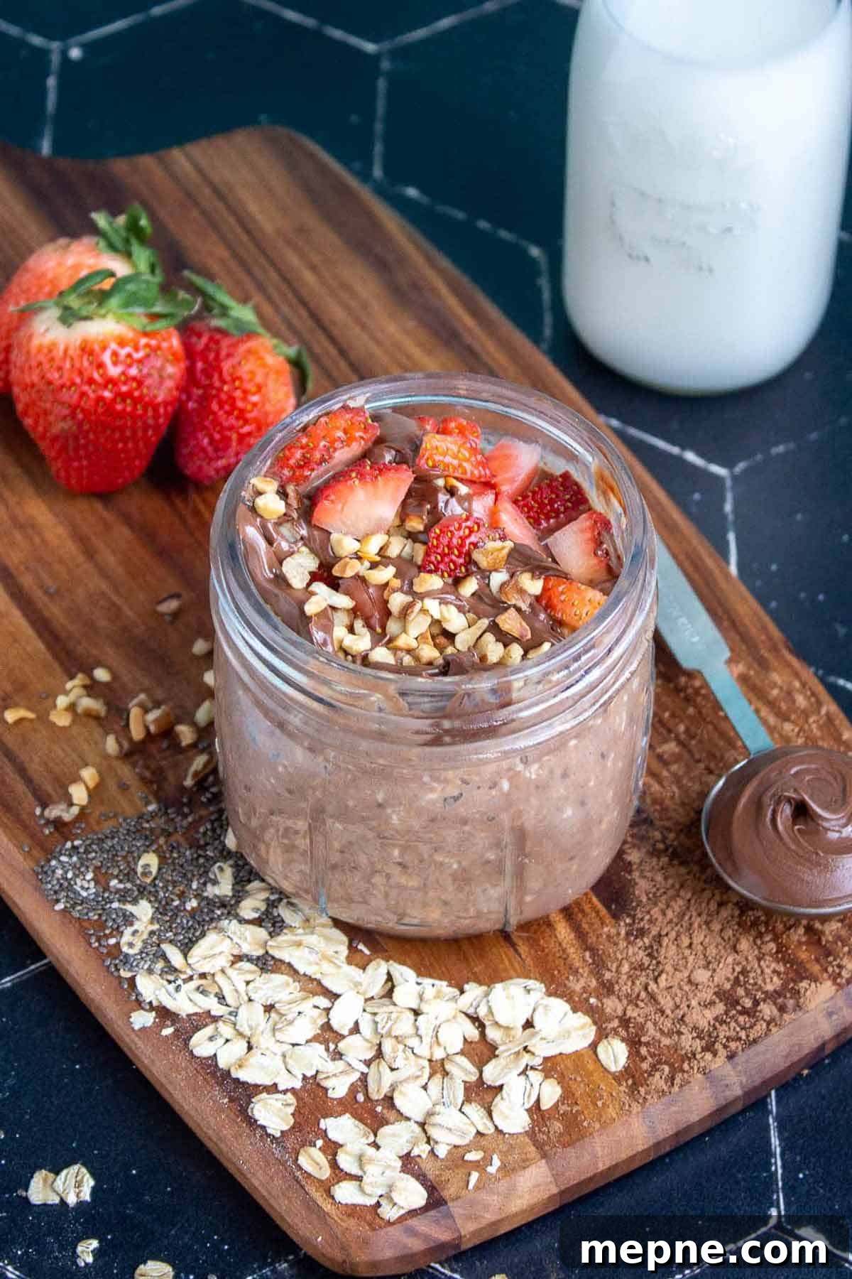 Nutella overnight oats in a mason jar topped with strawberries, Nutella, and hazelnuts.