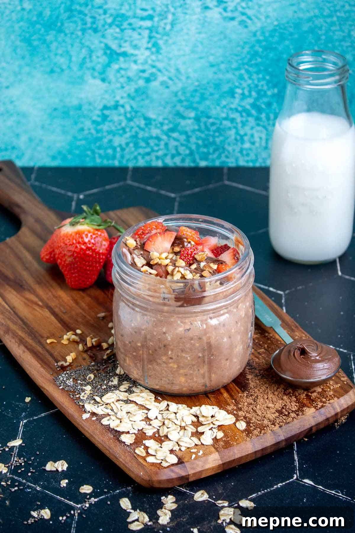 Nutella overnight oats in a mason jar topped with strawberries, Nutella, and hazelnuts.