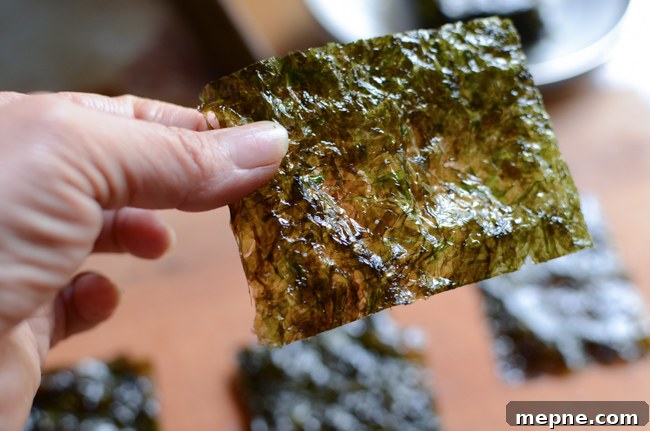 How to Make Crispy Roasted Seaweed Snacks at Home 8 A hand is holding a thin piece of roasted seaweed snack.