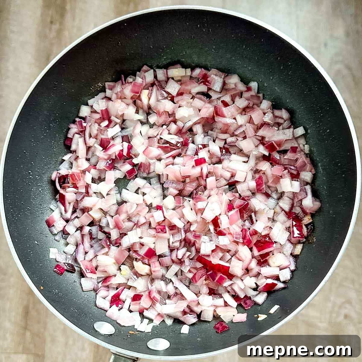 Authentic Bavarian Potato Salad with Bacon Recipe 11 chopped onion is shown cooking in a pan with bacon grease.