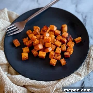 Cubed, sautéed sweet potatoes on a black plate