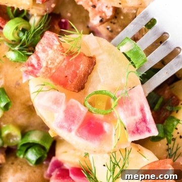 Authentic Bavarian Potato Salad with Bacon Recipe 24 A close-up of Bavarian potato salad with bacon pieces, red onions, green onions, and garnished with fresh dill.