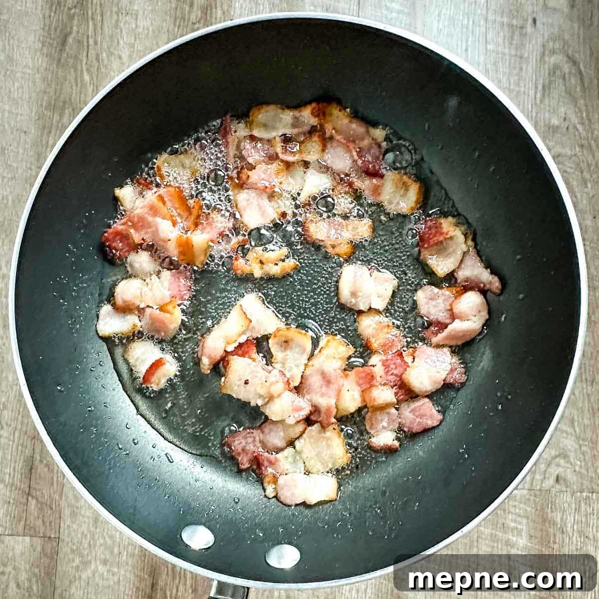 Authentic Bavarian Potato Salad with Bacon Recipe 10 bacon cooking in frying pan.
