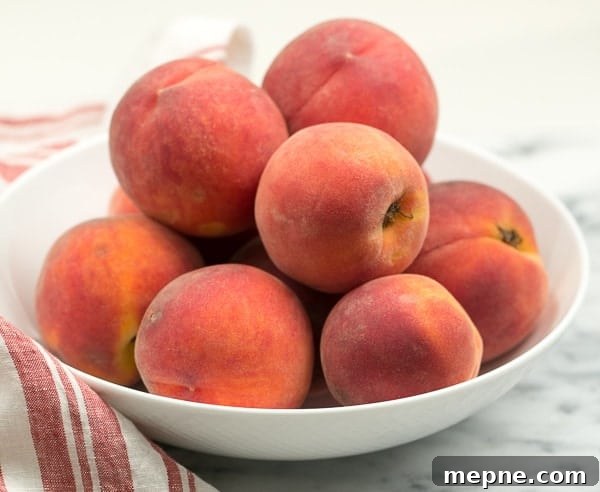 Peach Raspberry Crisp - A heavenly summer dessert that's easy and unforgettable!! A white bowl full of red haven peaches.
