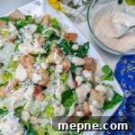caesar salad dressing on salad with dressing next to it