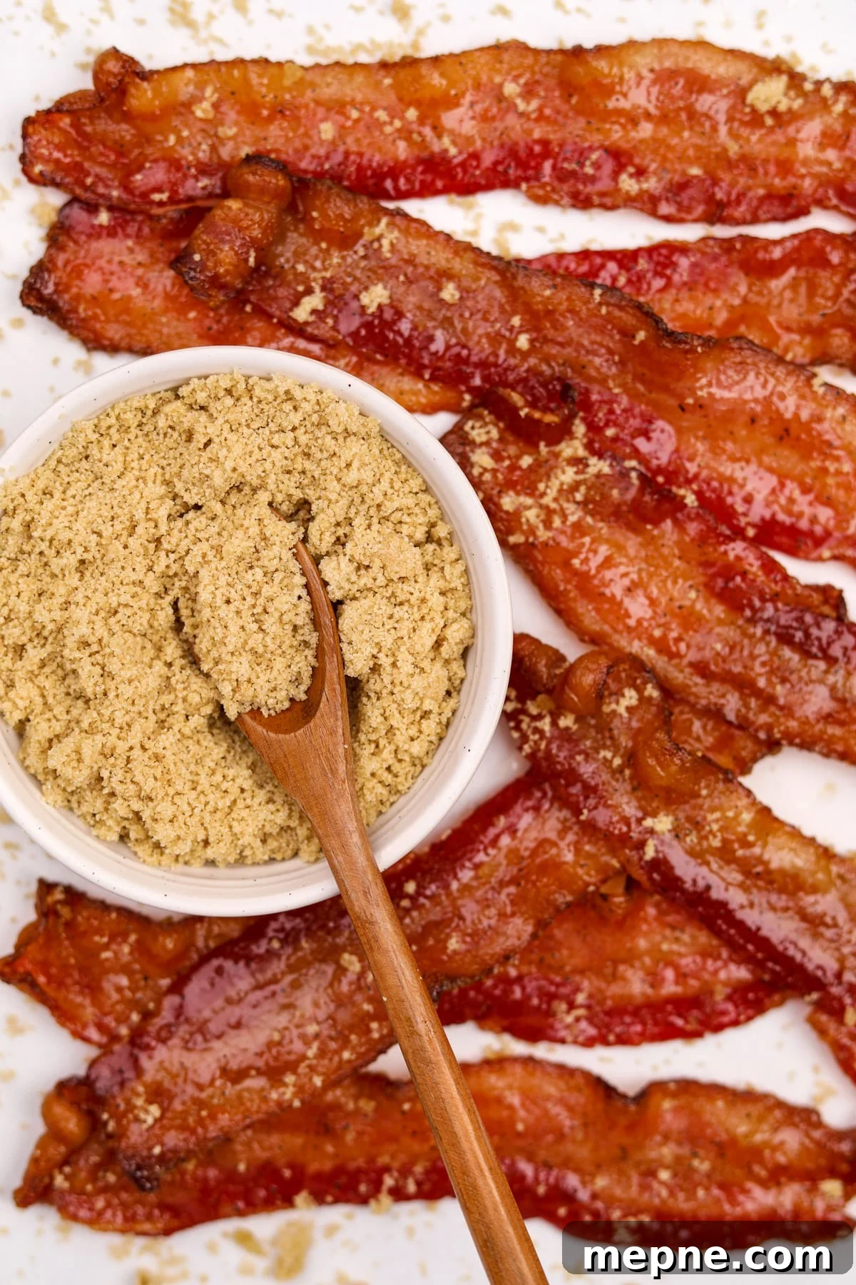 How to Make Candied Bacon: Sweet and Smoky Recipe 12 A small bowl of brown sugar surrounded by glazed bacon strips.