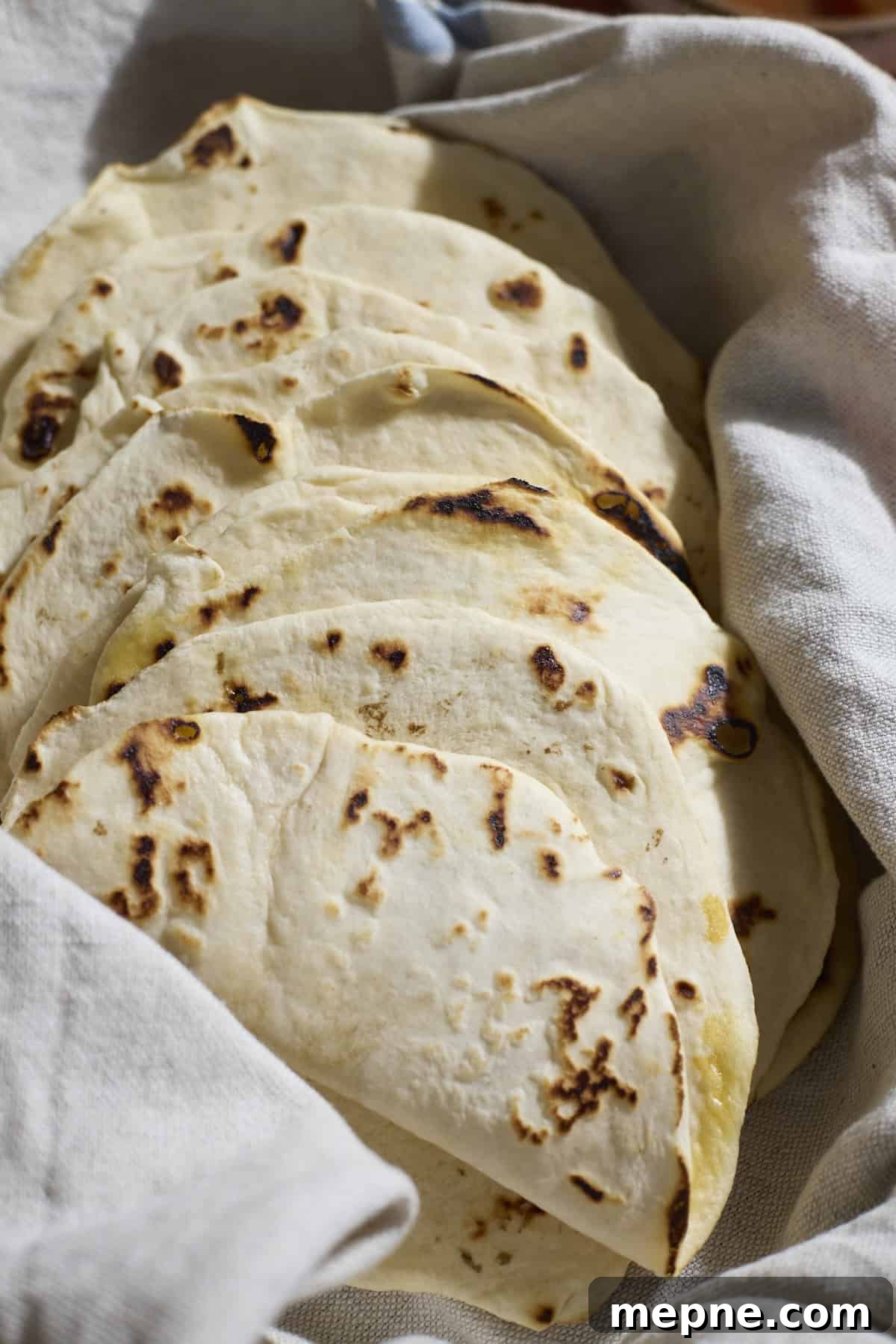 How to Make Sourdough Discard Tortillas 2 Sourdough Discard Tortillas wrapped in a kitchen towel.