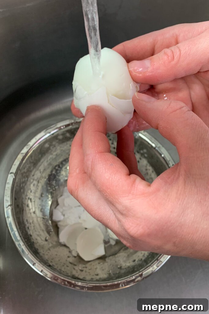 The easiest way to peel hard-boiled eggs is by running them under cold water while peeling them.