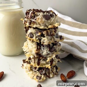 Almond joy cookies stacked on top of each other with a glass of milk in the background.