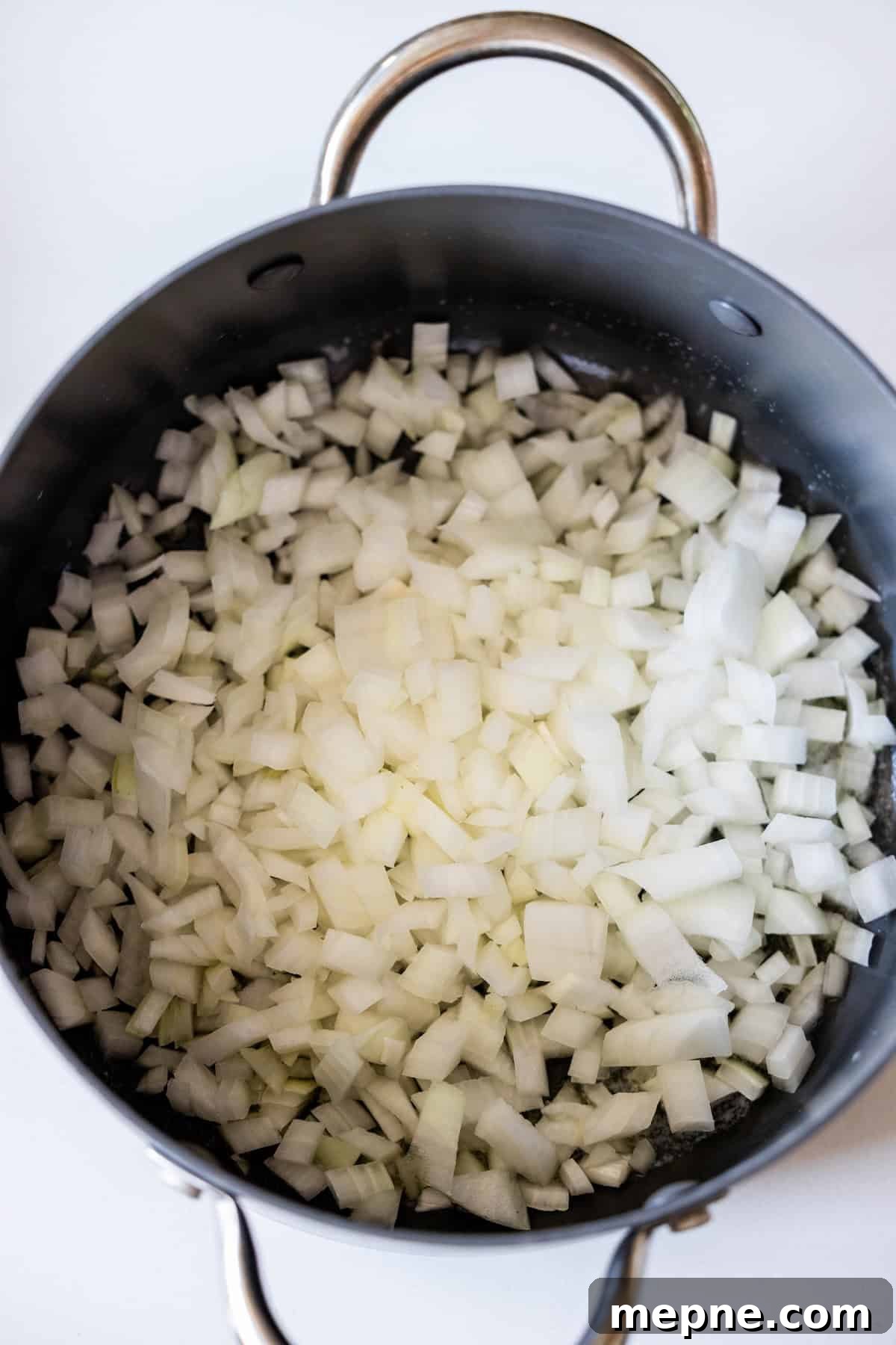 Creamy Tomato Orecchiette Pasta 5 Chopped white onions in a black pot with metal handles.