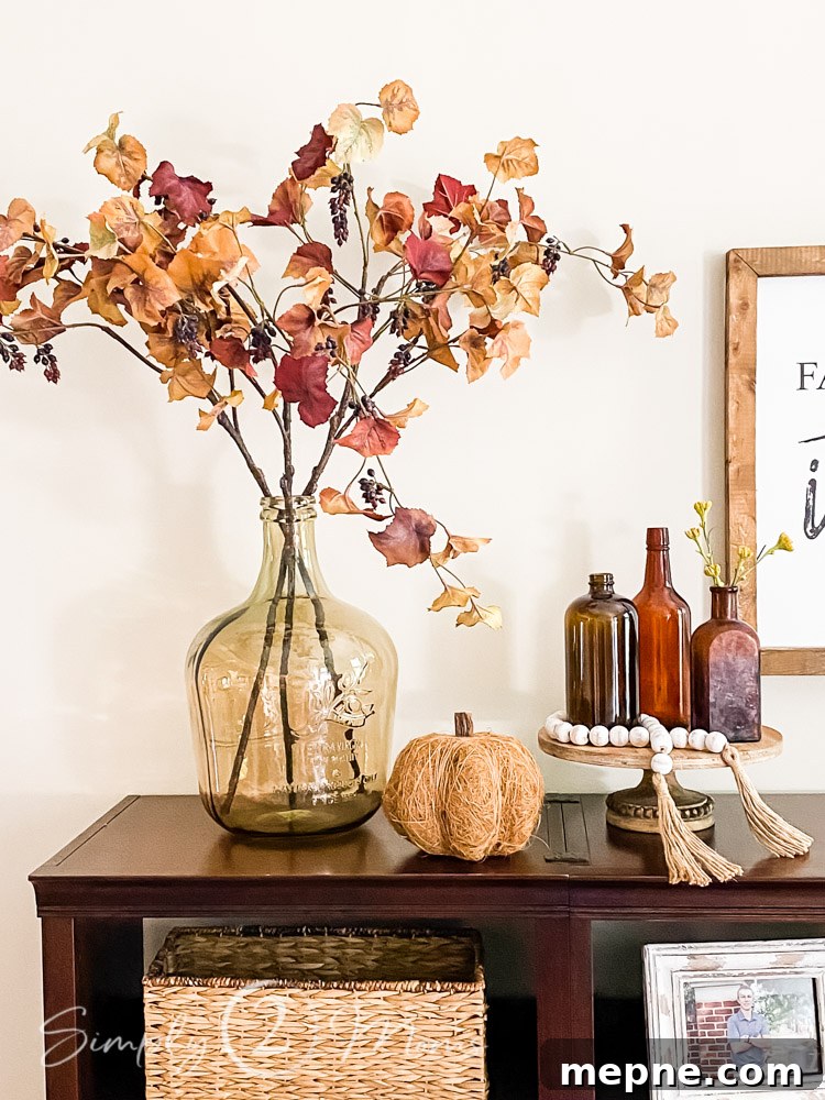 display of glass vase with fall leaves pumpkin and trio of amber vintage glass bottle on top of shelf