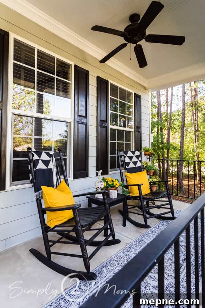 rocking chairs on a covered front porch with pillows and throws on them. Lanterns sitting beside the rockers.