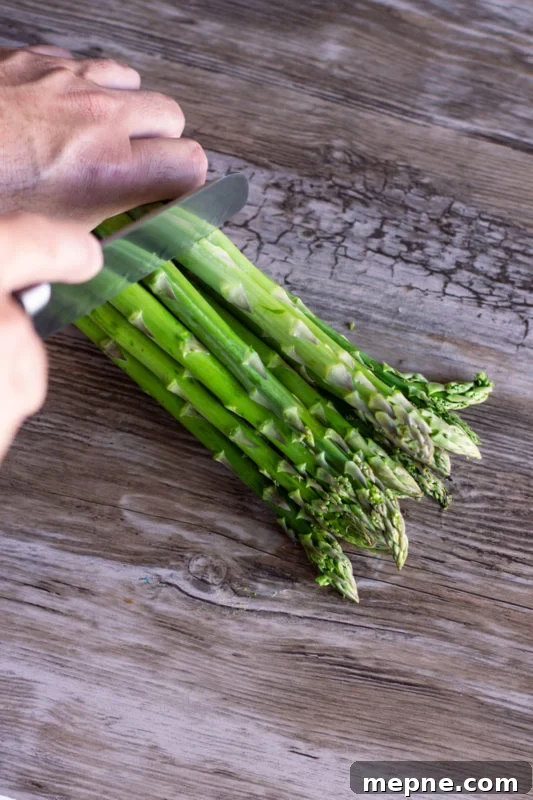 Crispy Oven Roasted Vegetables with Garlic and Herbs 4 Person chopping the stems off fresh asparagus.