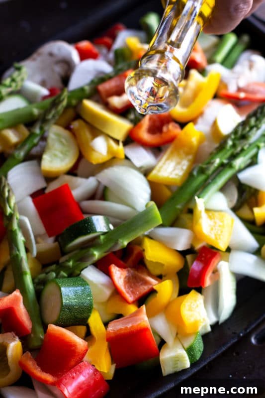Crispy Oven Roasted Vegetables with Garlic and Herbs 6 Drizzling olive oil over a pan of chopped vegetables including asparagus, pepper, zucchini and squash.