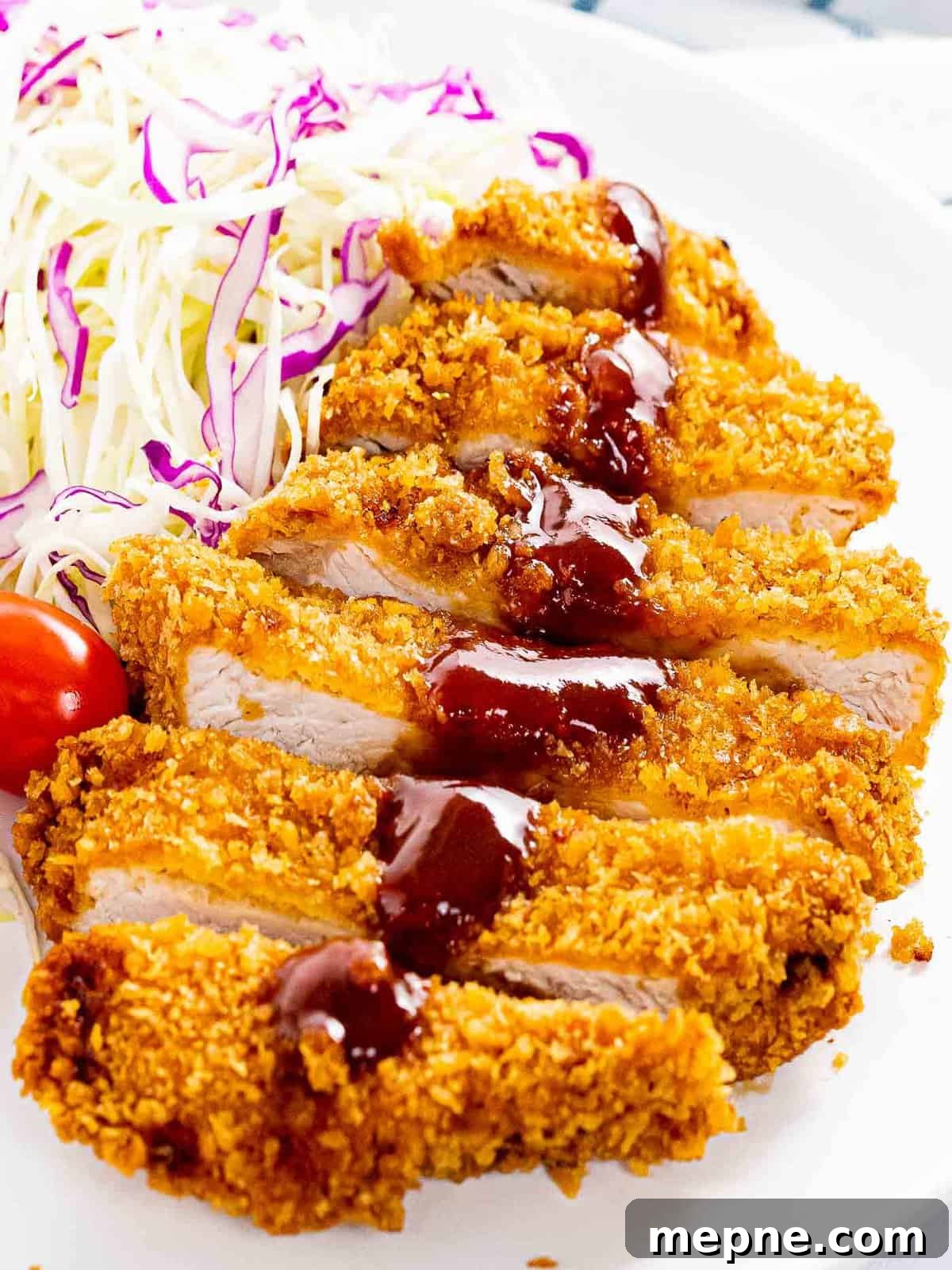 Tonkatsu with crunchy panko breadcrumbs with tonkatsu sauce next to shredded cabbage.