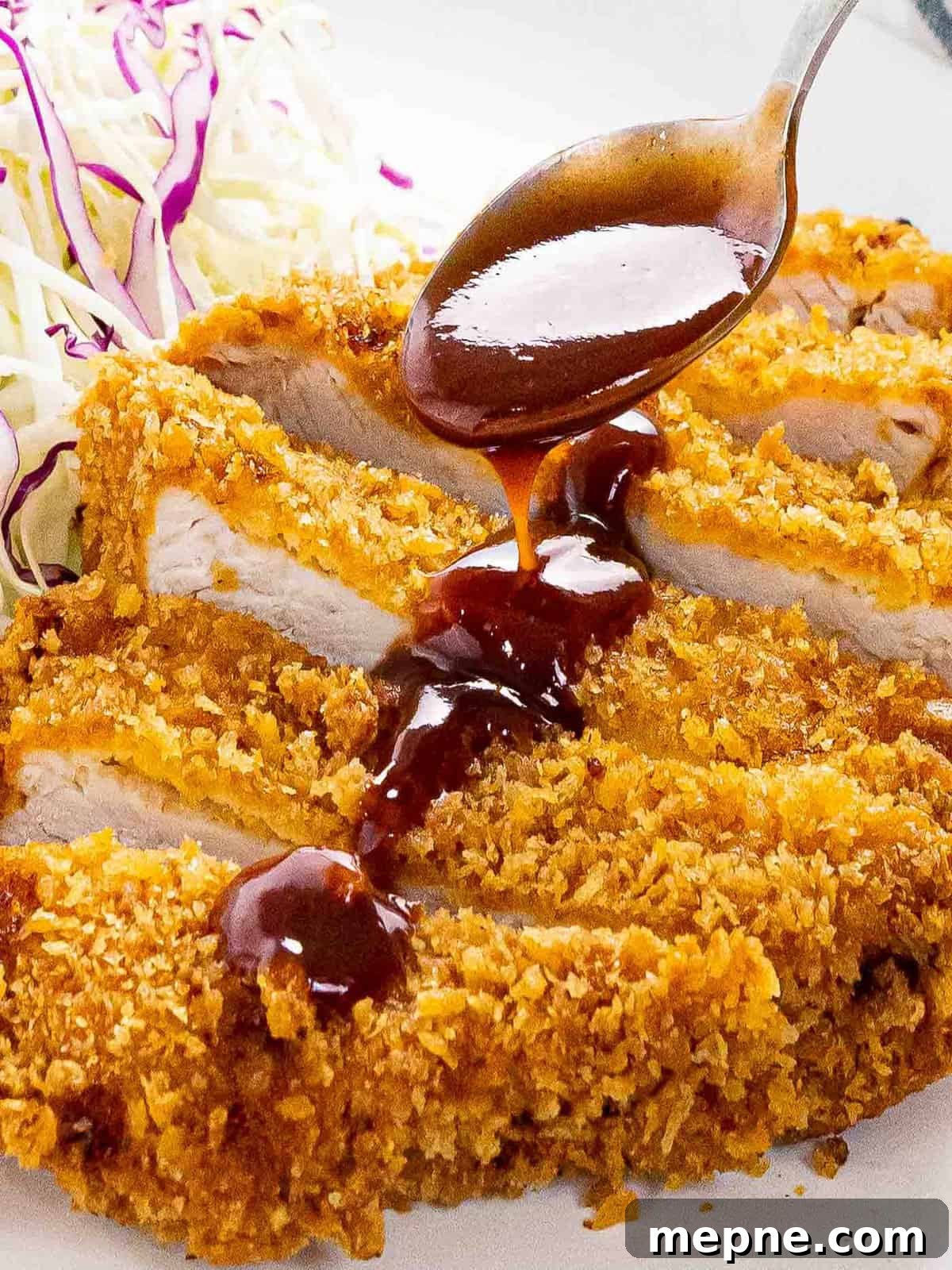 Tonkatsu sauce being drizzled onto crispy slices of tonkatsu.