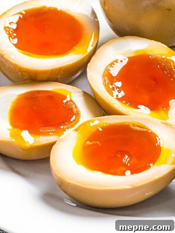 Ramen eggs marinated in soy sauce cut in half to reveal soft boiled eggs with runny yolks.