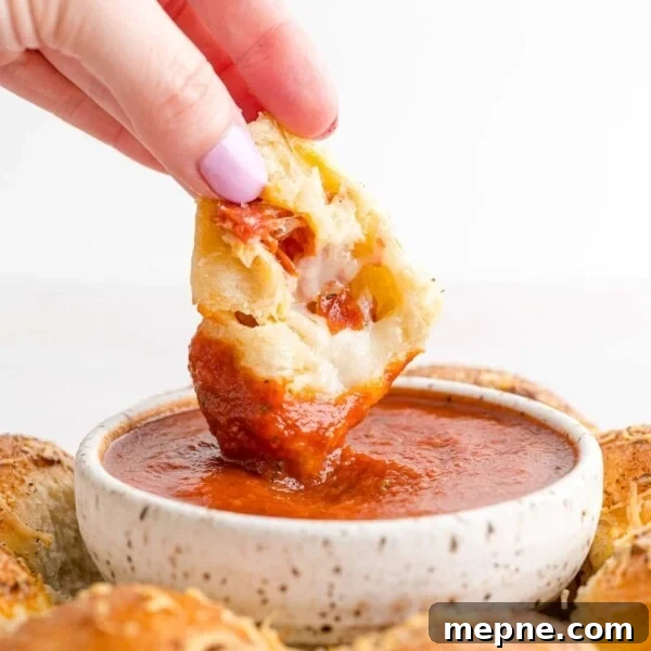 Stuffed pizza bite being dipped into marinara sauce.