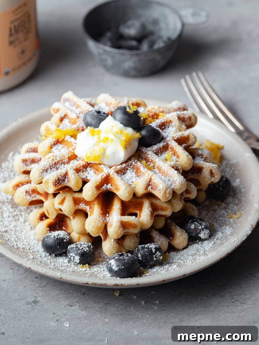 Crispy Gluten Free Waffles Recipe 7 close up of sour cream waffles, gluten free waffles topped with powdered sugar, sour cream and fresh berries