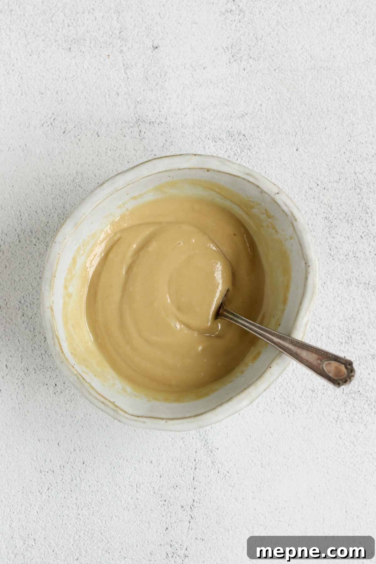 Creamy Maple Tahini Dressing for Salads and Grain Bowls 6 Maple tahini dressing mixed in a shallow bowl with a fork in the bowl.