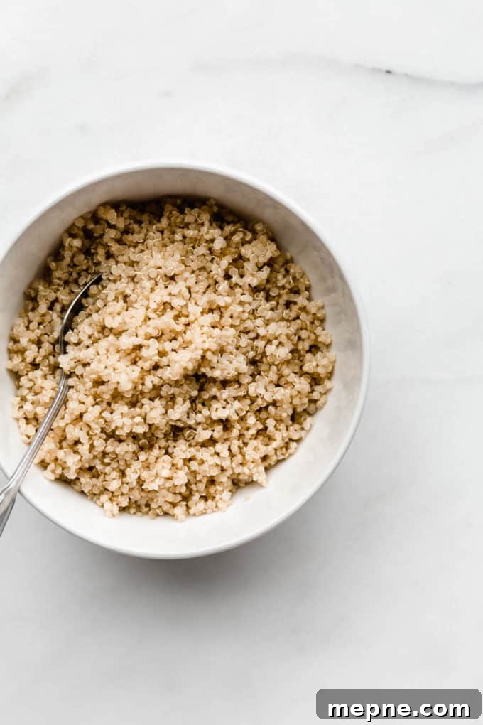 Protein-Packed Quinoa Breakfast Bowl with Avocado and Eggs 3 Cooked quinoa in a white bowl