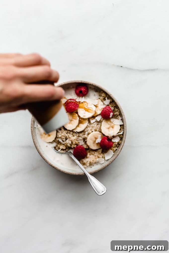 Protein-Packed Quinoa Breakfast Bowl with Avocado and Eggs 4 A hand pouring maple syrup onto a bowl of breakfast quinoa