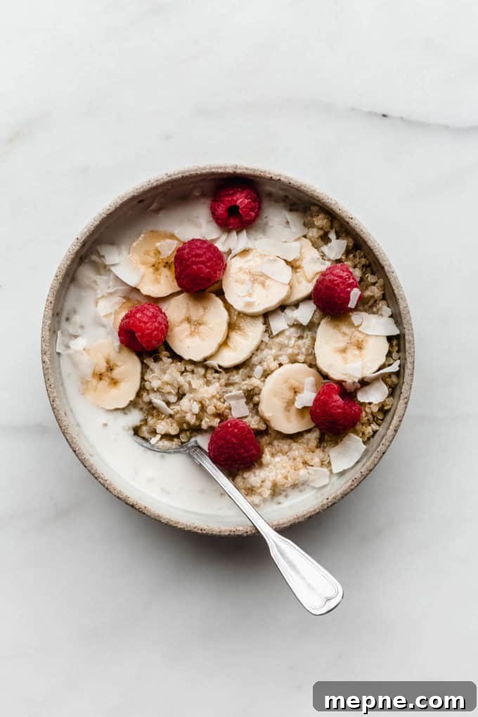 Protein-Packed Quinoa Breakfast Bowl with Avocado and Eggs 5 Quinoa in a ceramic bowl with coconut milk bananas and berries in it