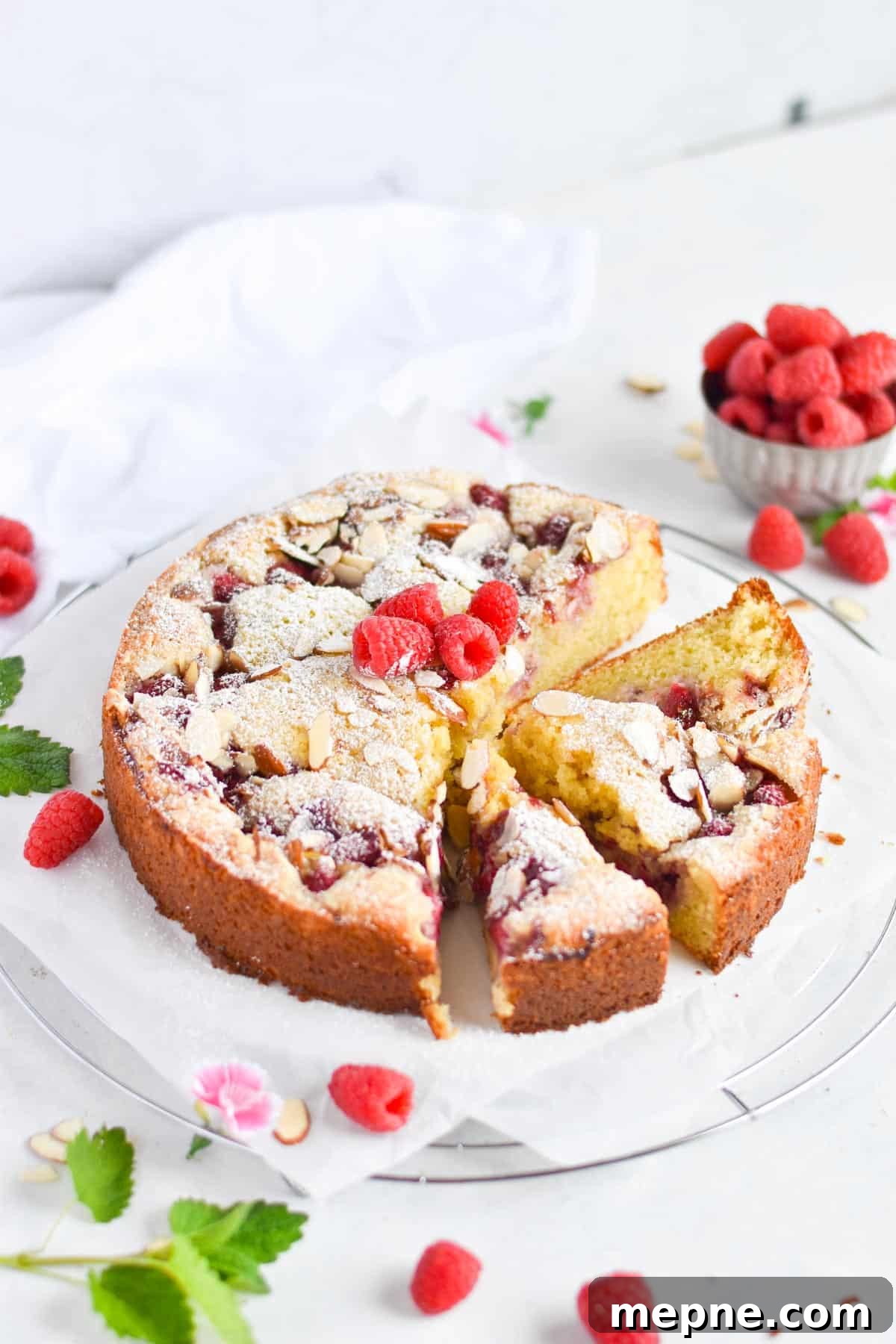 whole cake sliced with fresh raspberries on top. 