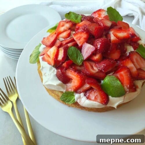 white platter of strawberry shortbread cake with whipped cream and fresh strawberries