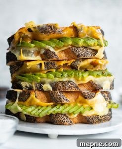 Avocado Grilled Cheese 3 sandwiches stacked on each other on small marble plate