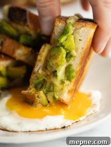 Avocado Grilled Cheese close up shot of sandwich being dunked into fried egg