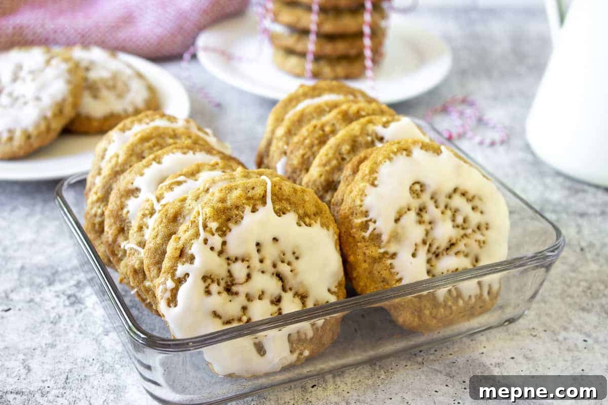 Old-Fashioned Iced Oatmeal Cookies Recipe 3 Iced cookies stacked in a glass container.