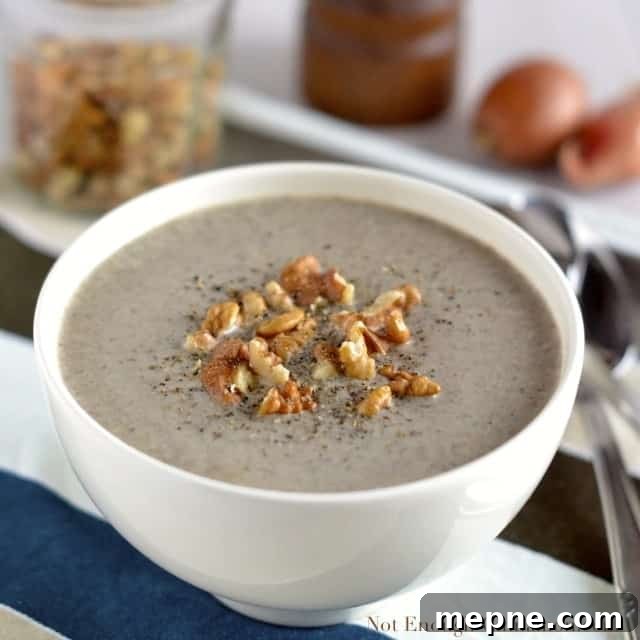 Skinny Cream of Mushroom Soup served in a white bowl with some chopped walnuts and freshly grated pepper on top