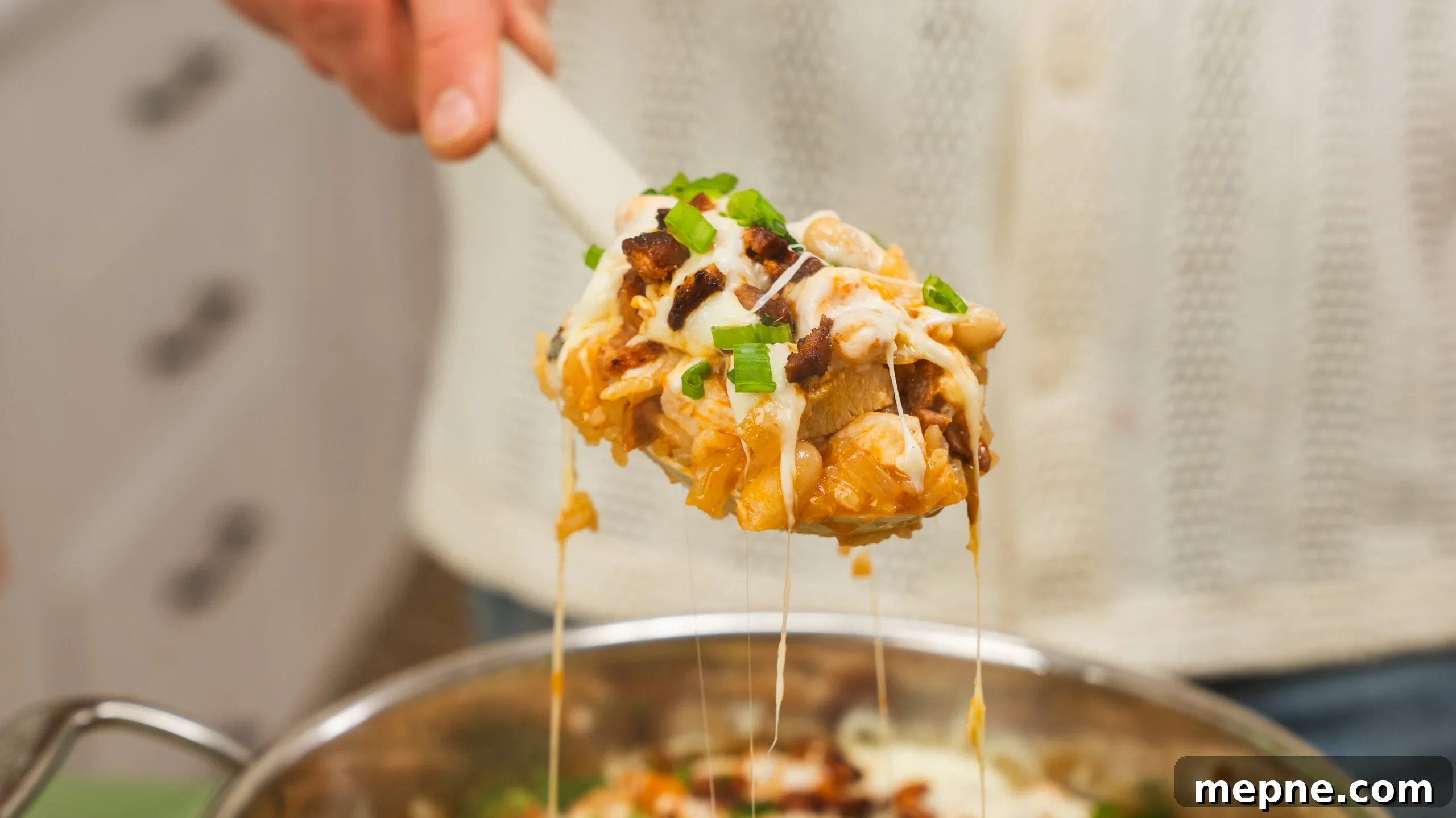 20-Minute Cheesy Chicken and Rice with Chorizo 7 Scoop of cheesy chicken and rice being lifted from a skillet