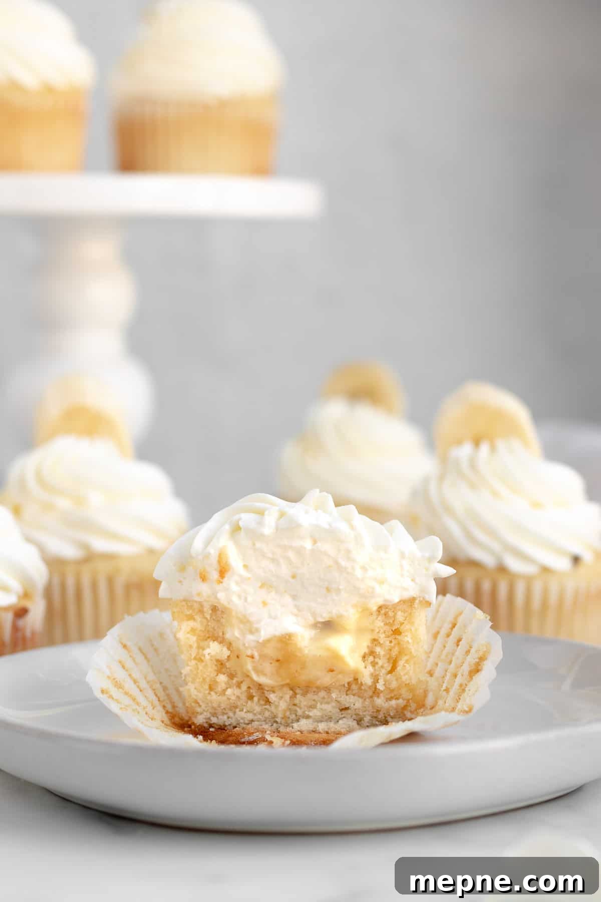 Creamy Banana Pudding Cupcakes with Vanilla Frosting 7 banana pudding cupcake cut in half to show banana pudding filling