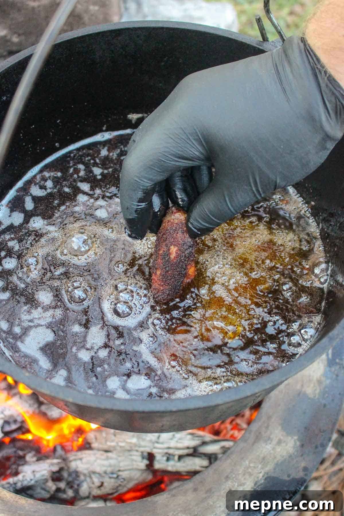 Adding a chicken wing to the frying oil.