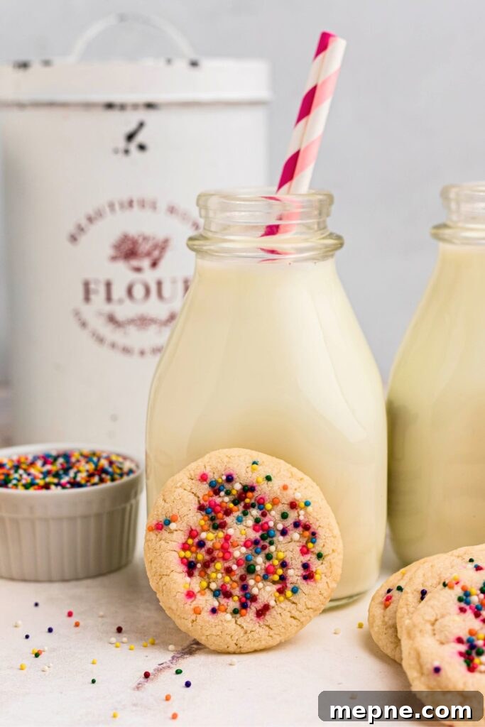 3 Ingredient Sugar Cookies Recipe 2 Sugar cookie with sprinkles leaning up against a small bottle of milk with pink straws.