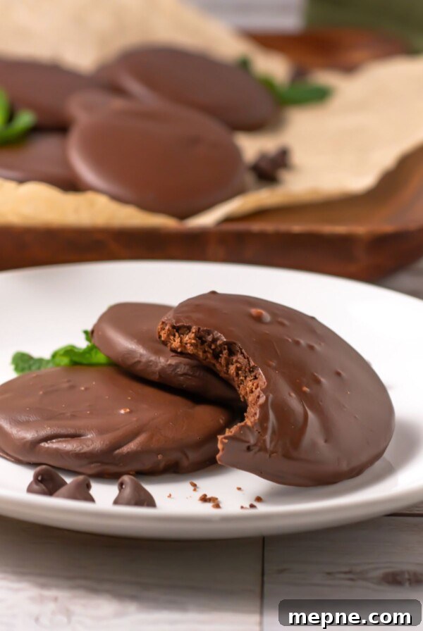 3 Ingredient Sugar Cookies Recipe 11 Chocolate round cookies, dipped in cookies, on a small white plate with the top cookie missing a bite.