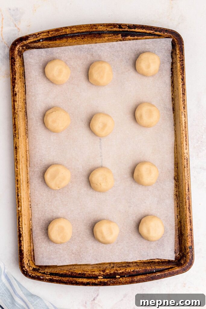3 Ingredient Sugar Cookies Recipe 5 Rolled sugar cookie dough balls on a baking sheet lined with parchment paper.