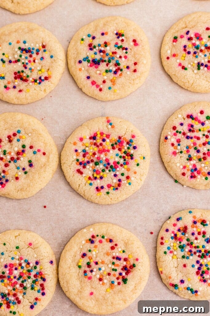 3 Ingredient Sugar Cookies Recipe 6 Baked sugar cookies with sprinkles on parchment paper.