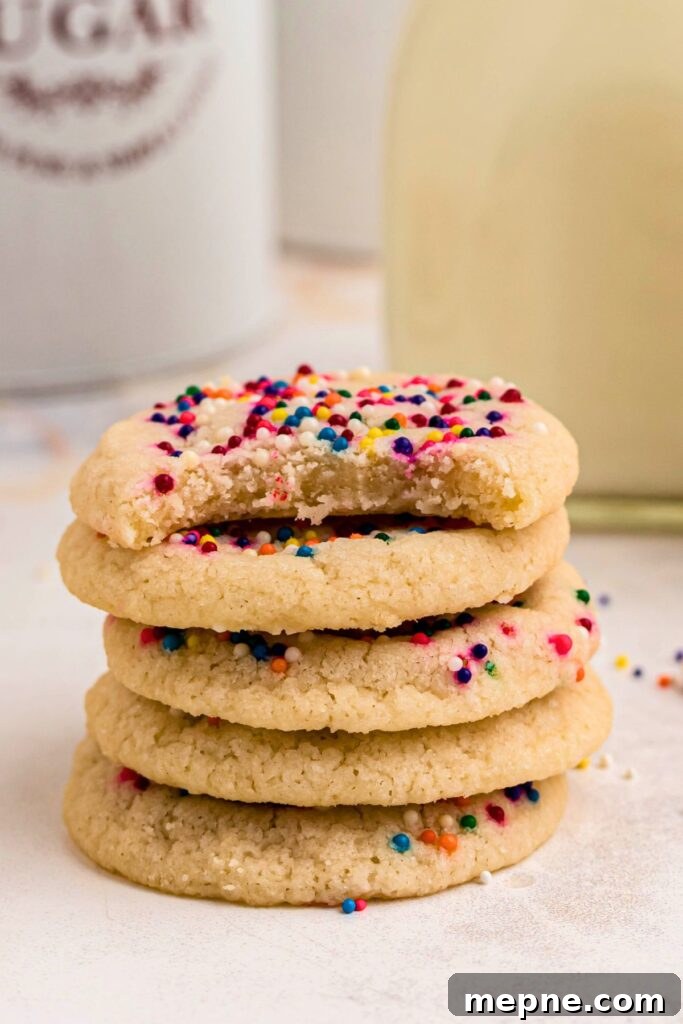 3 Ingredient Sugar Cookies Recipe 7 Small stack of sugar cookies with sprinkles, with the top cookie missing a bite.