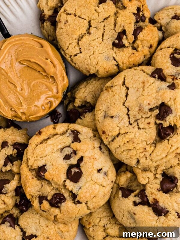 3 Ingredient Sugar Cookies Recipe 8 Peanut butter chocolate chip cookies on a white plate with a scoop of peanut butter next the cookies.